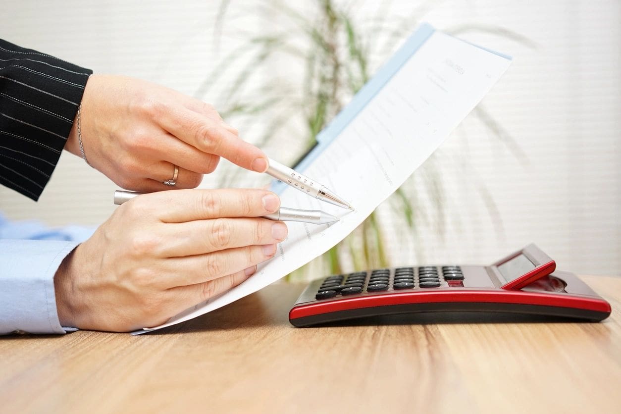 Person reviewing documents with a calculator on the table.